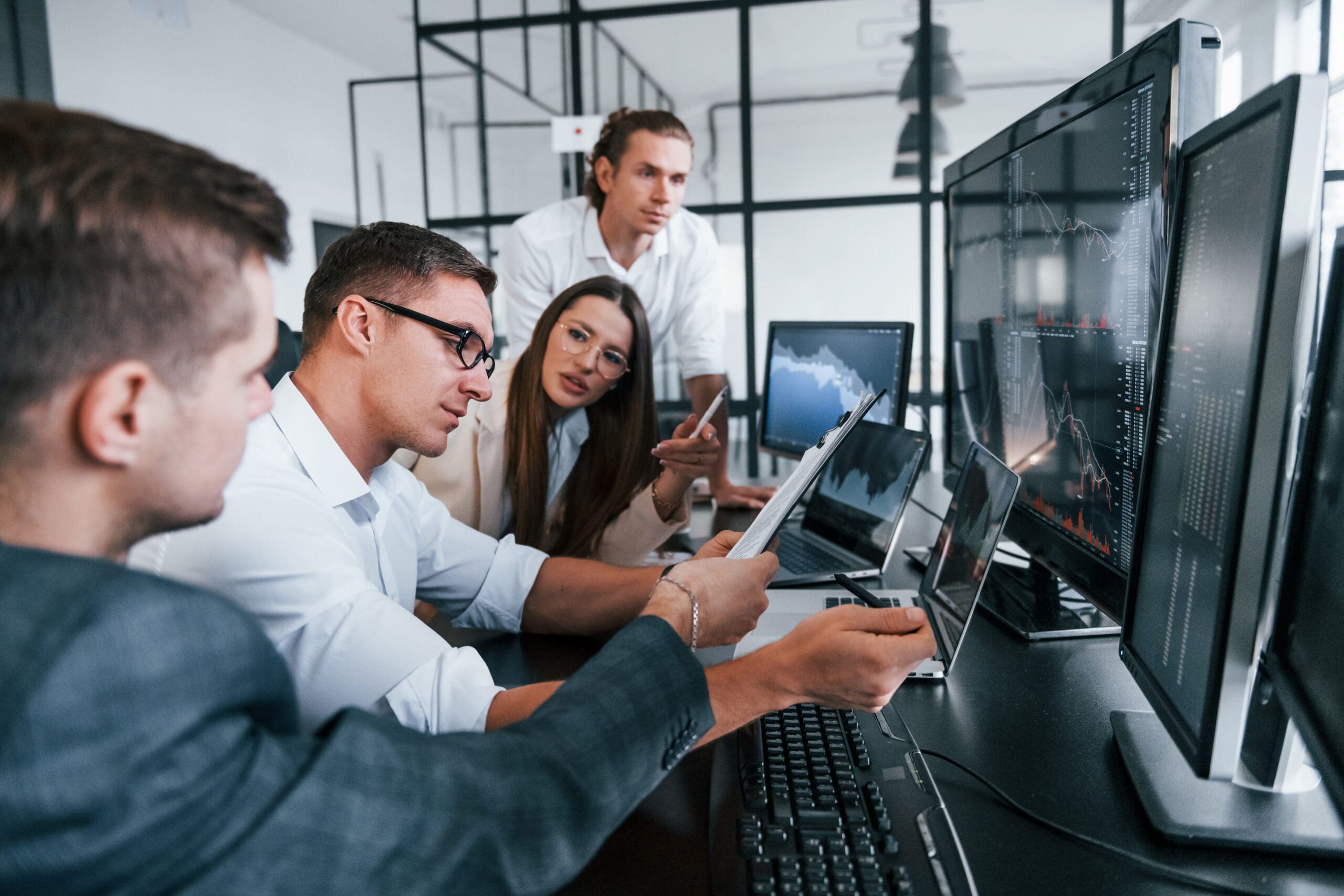 Analysing information. Team of stockbrokers works in modern office with many display screens